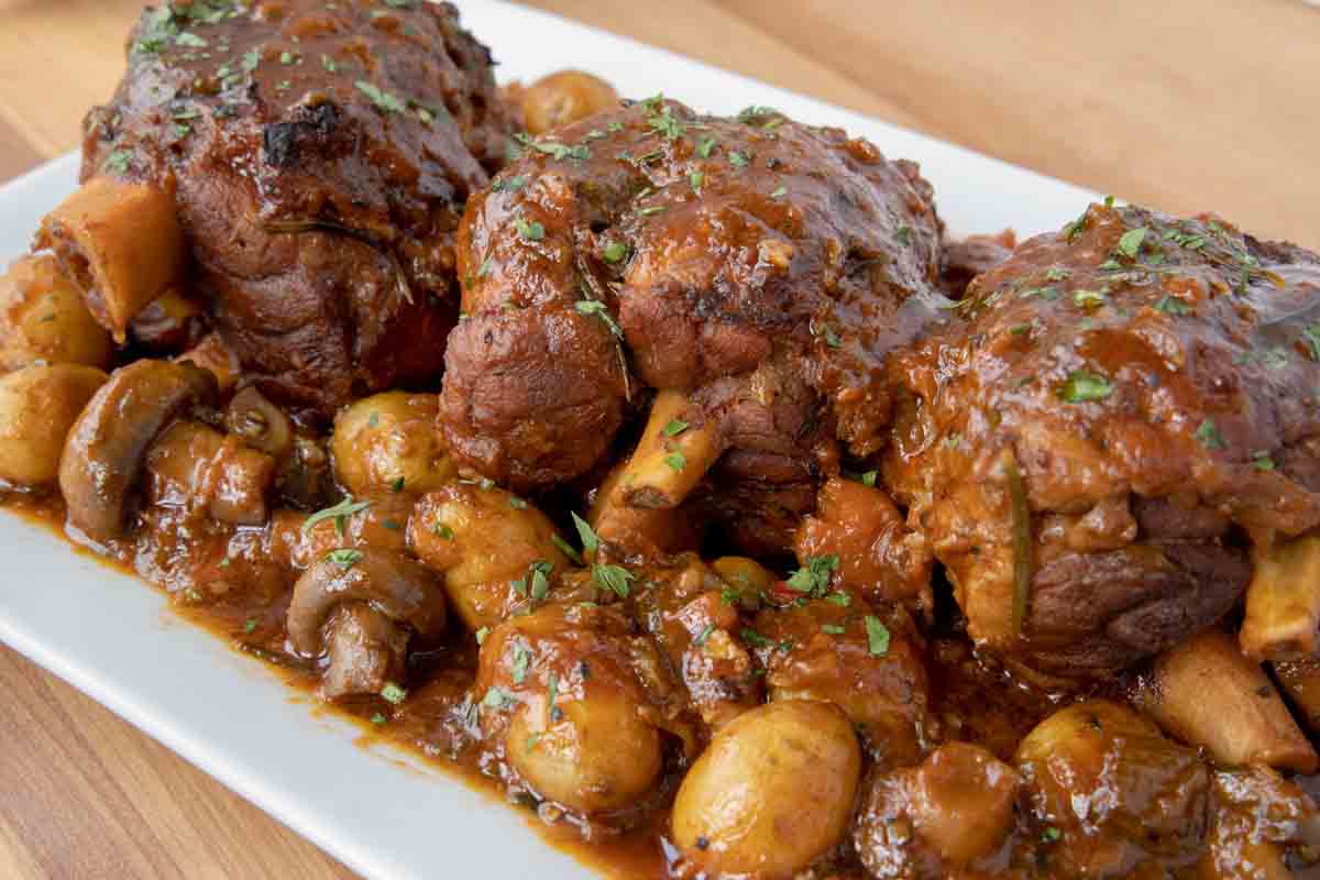 3 pork shanks with veggies on a white platter