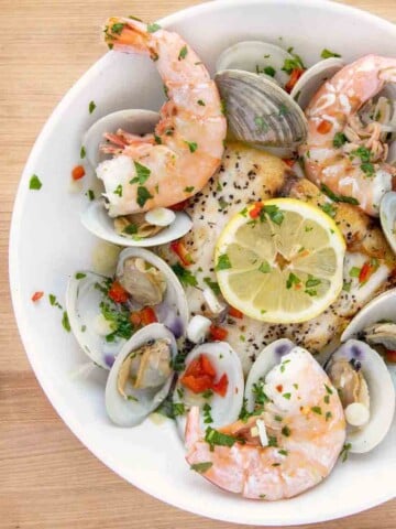 overhead partial view of a white bowl of barramundi with clams and shrimp