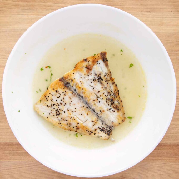 barramundi and broth in a shallow white bowl