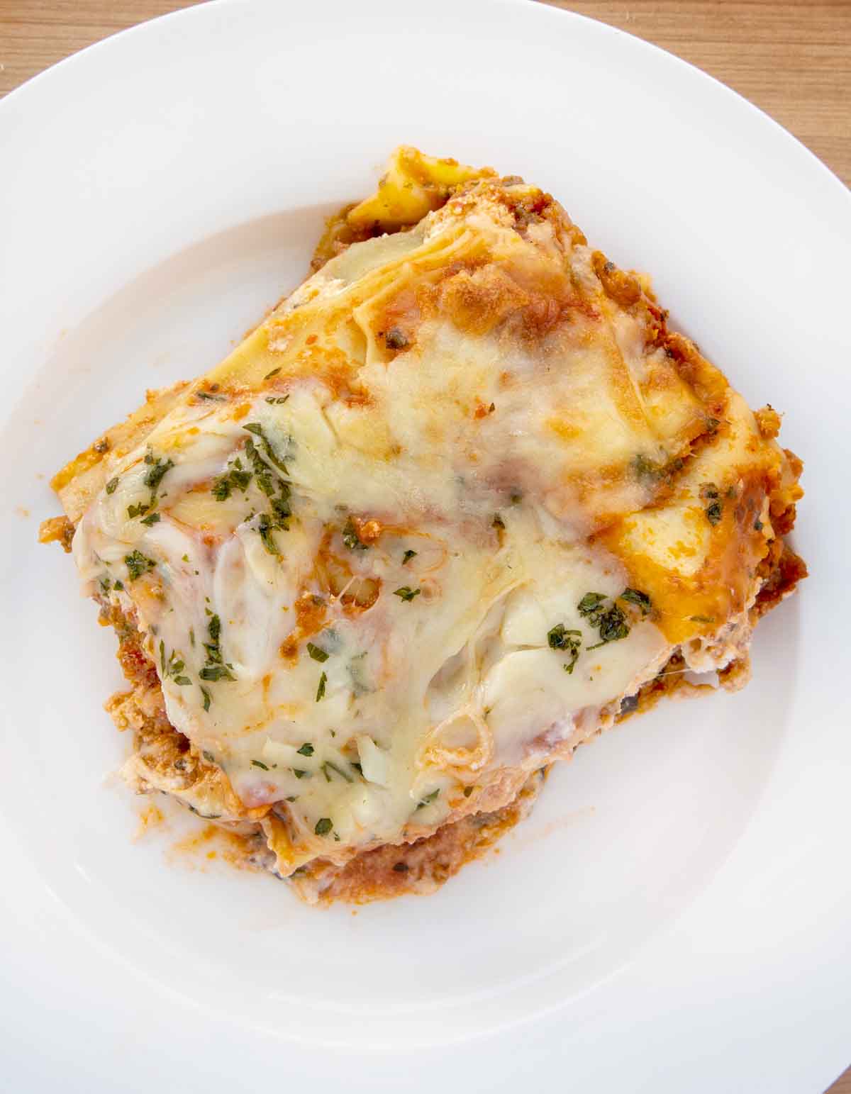 overhead shot of lasagna bolognese on a white plate