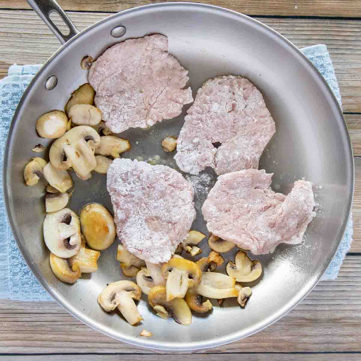 floured medallions being added to a pan with sautéed mushrooms.