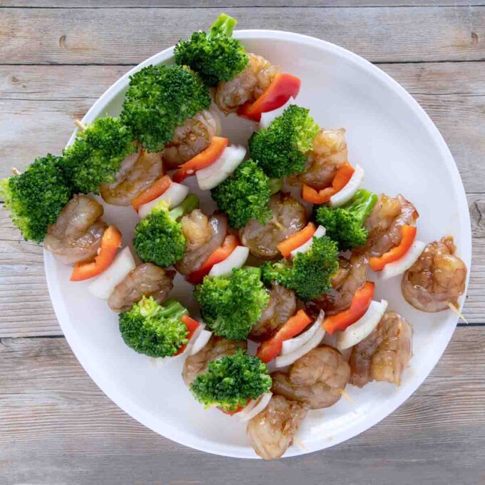 shrimp and broccoli skewers on a white plate