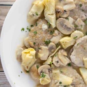 partial overhead view of veal piccata on a white plate