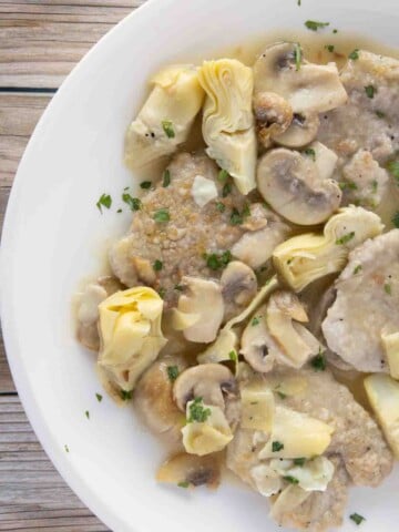 partial overhead view of veal piccata on a white plate