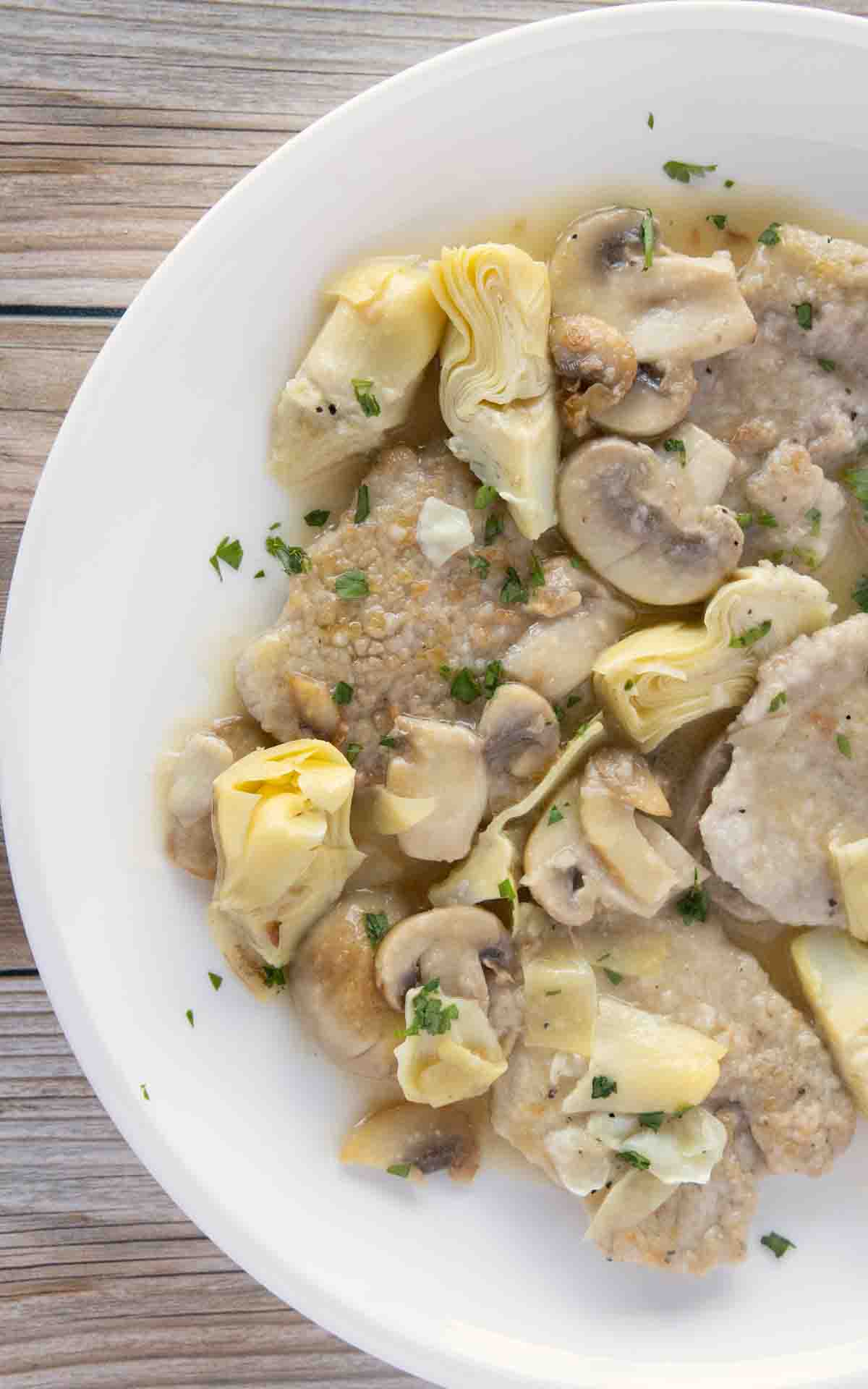 partial overhead view of veal piccata on a white plate.