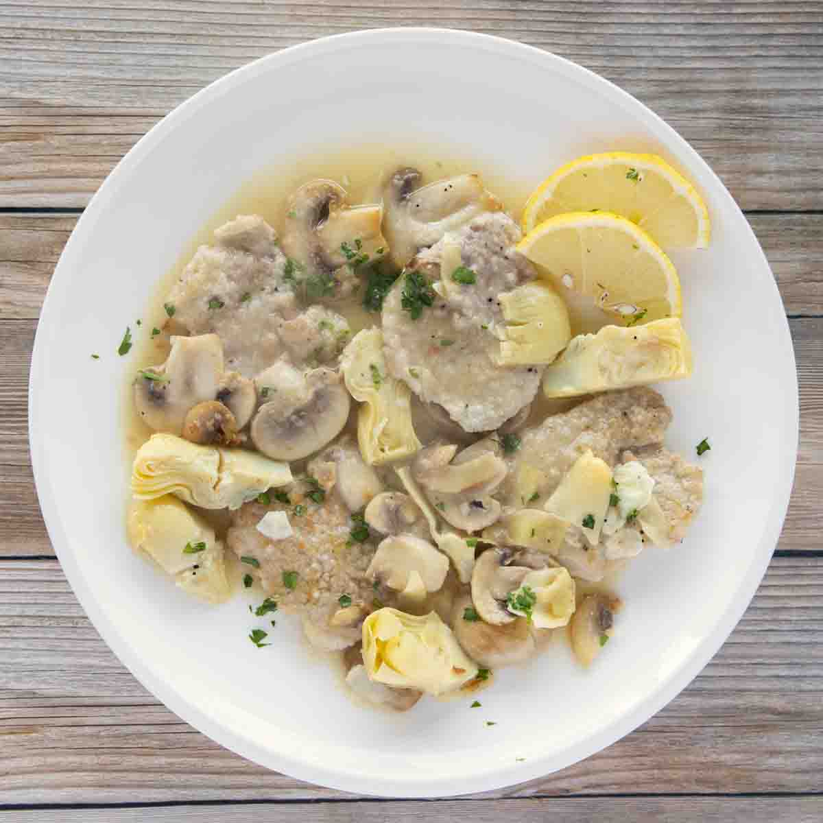overhead view of veal piccata on white plate
