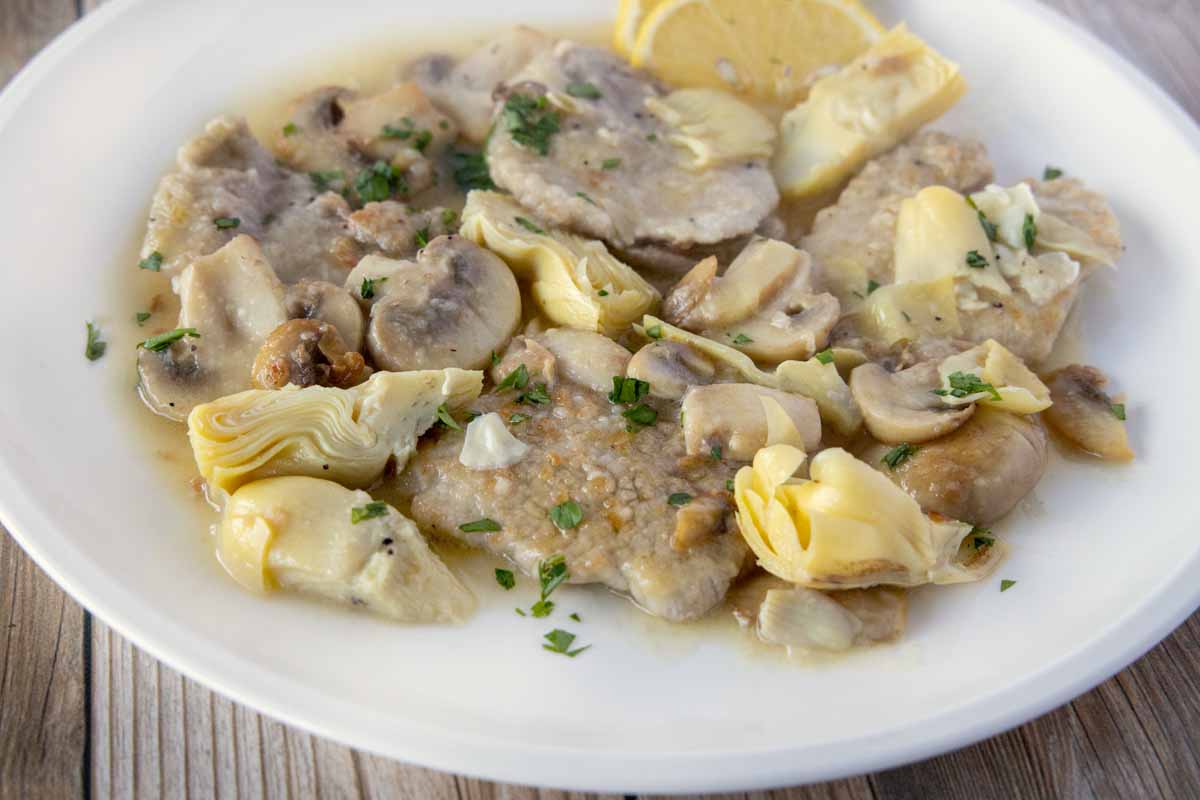 close up of veal piccata on a white plate.