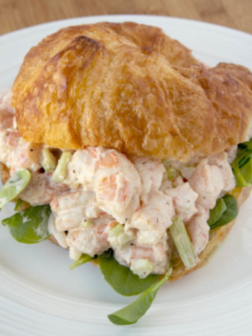 shrimp salad on a croissant on a white plate
