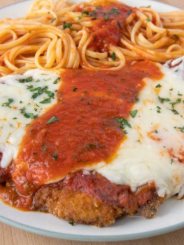 chicken parm with pasta on a white plate