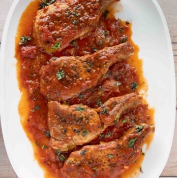 overhead view of four Sicilian pork chops on a white platter