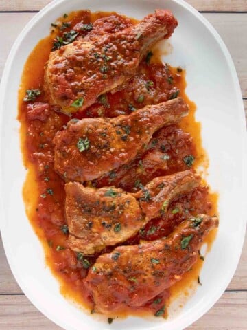 overhead view of four Sicilian pork chops on a white platter
