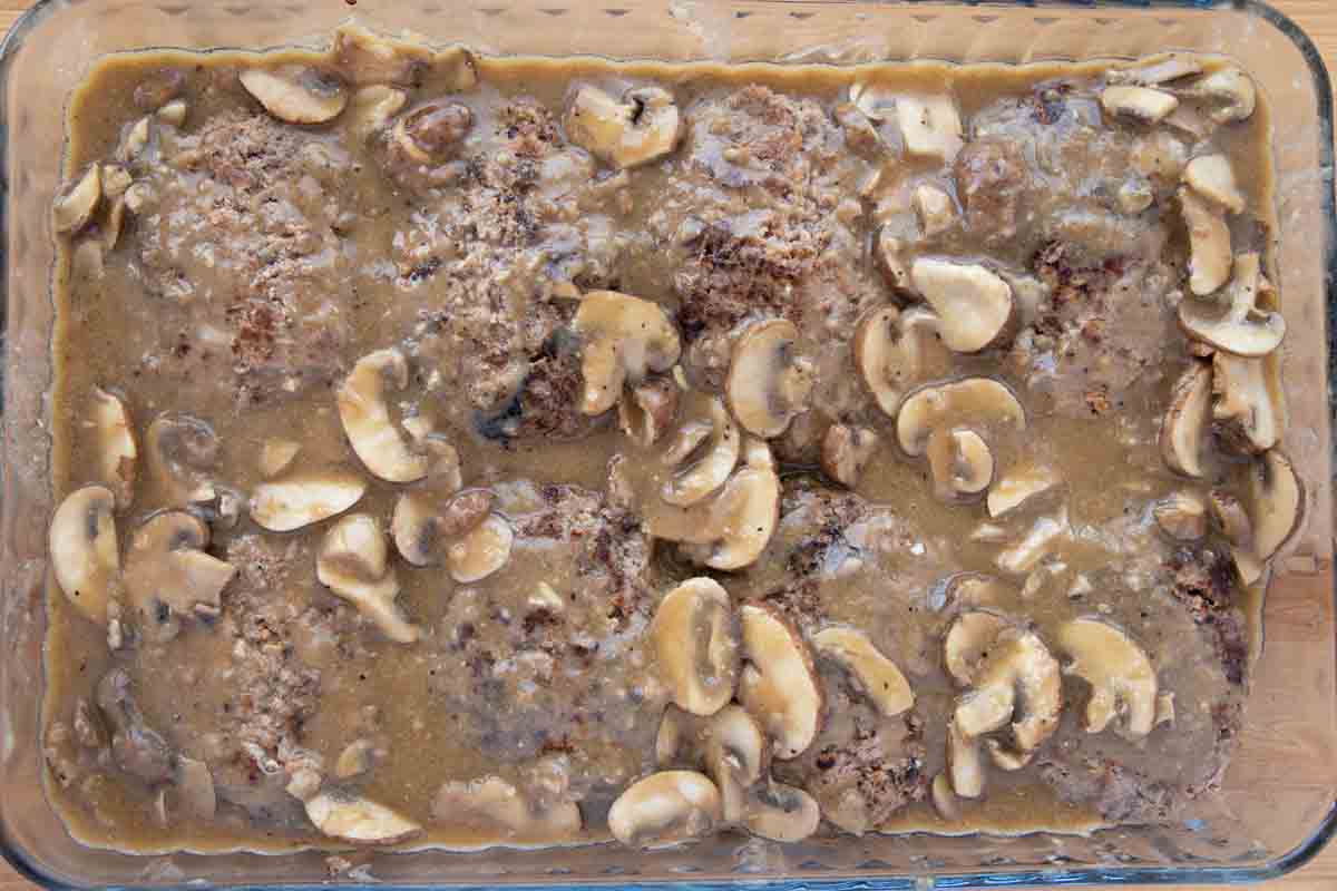 mushroom sauce added to baking dish with salisbury steaks