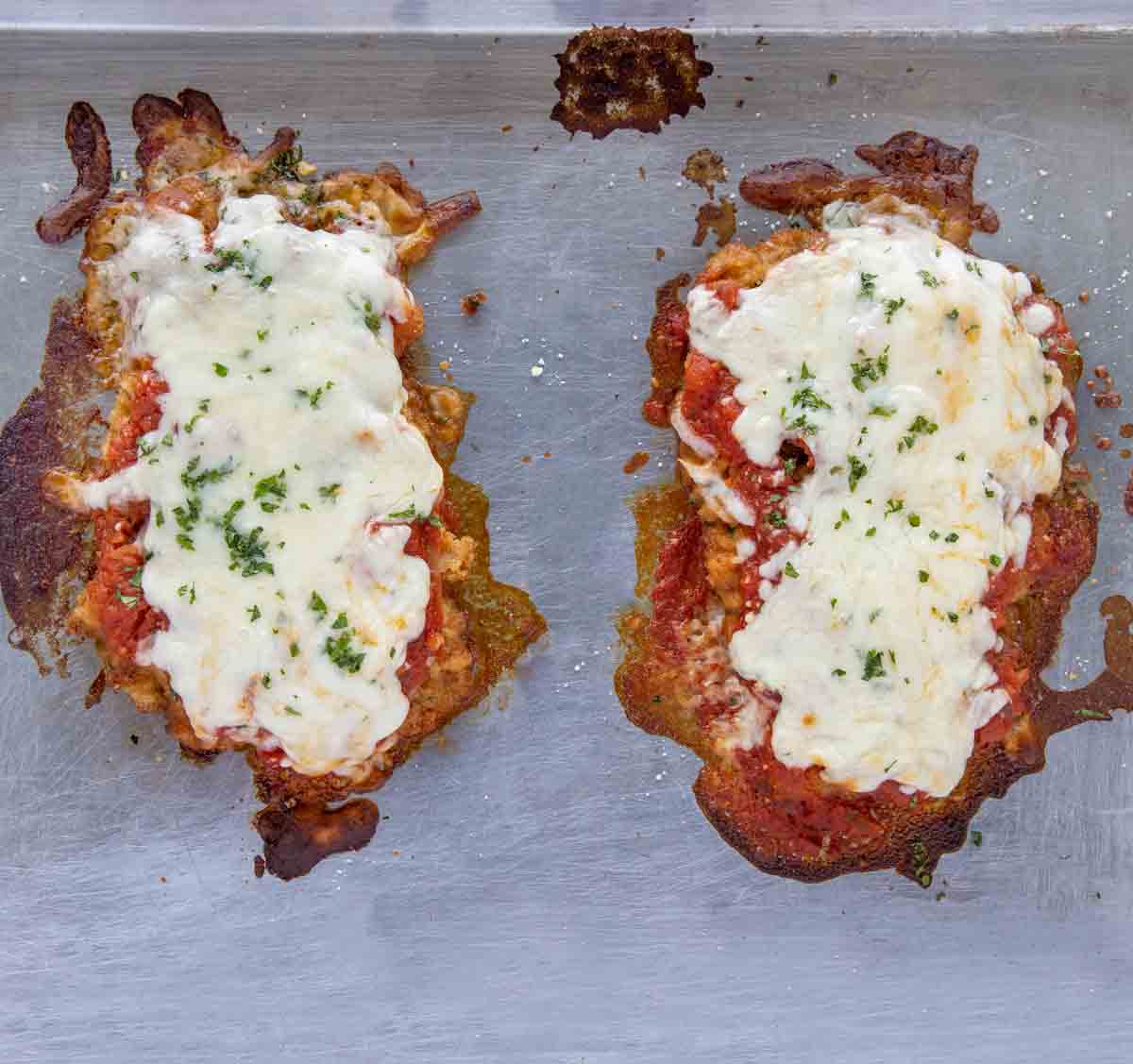 fully cooked veal parm on a silver baking sheet
