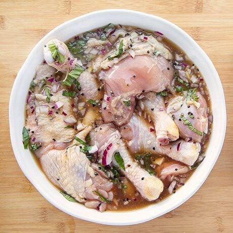 bowl with chicken marinating next to a box of Oregon Chai on a wooden cutting board