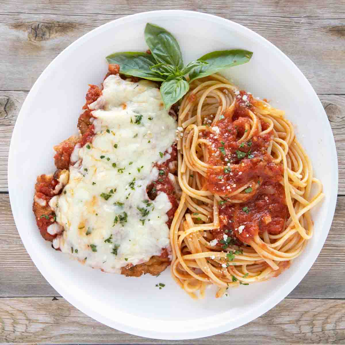 overhead view of veal parm and linguine white plate
