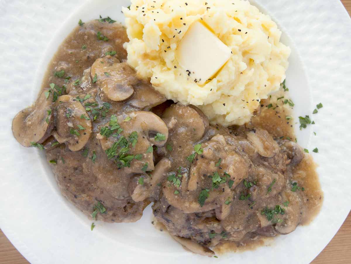 salisbury steak with mashed potatoes on a white plate with mashed potatoes