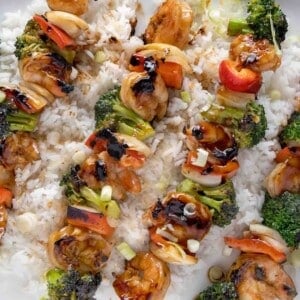 shrimp and broccoli skewers on a bed of jasmin rice on a white platter