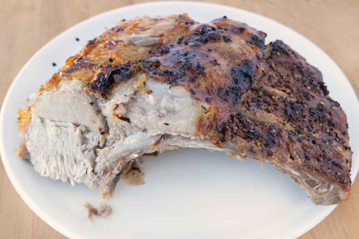 side view of a roasted rack of tomahawk chops on a white platter