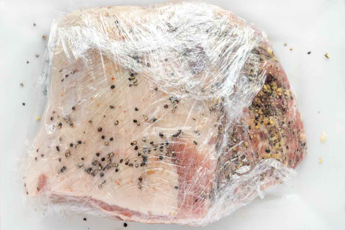 seasoned rack of pork wrapped in plastic wrap