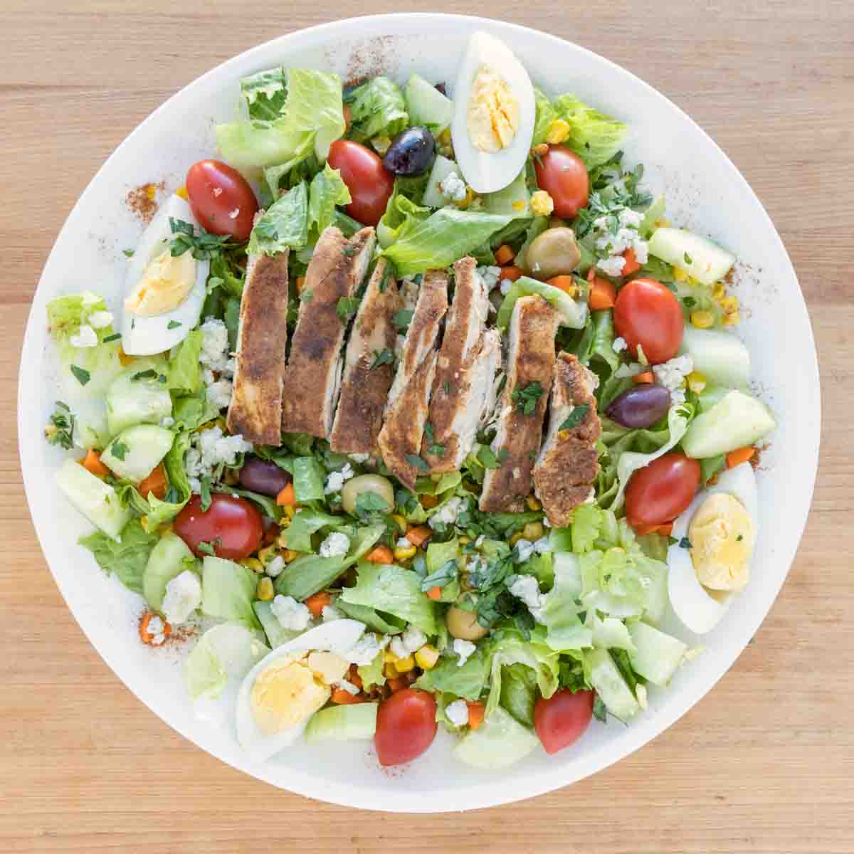 Plate of finished salad with blackened chicken on top