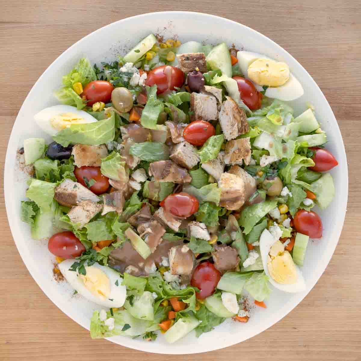 blackened chicken salad with dressing in a white bowl