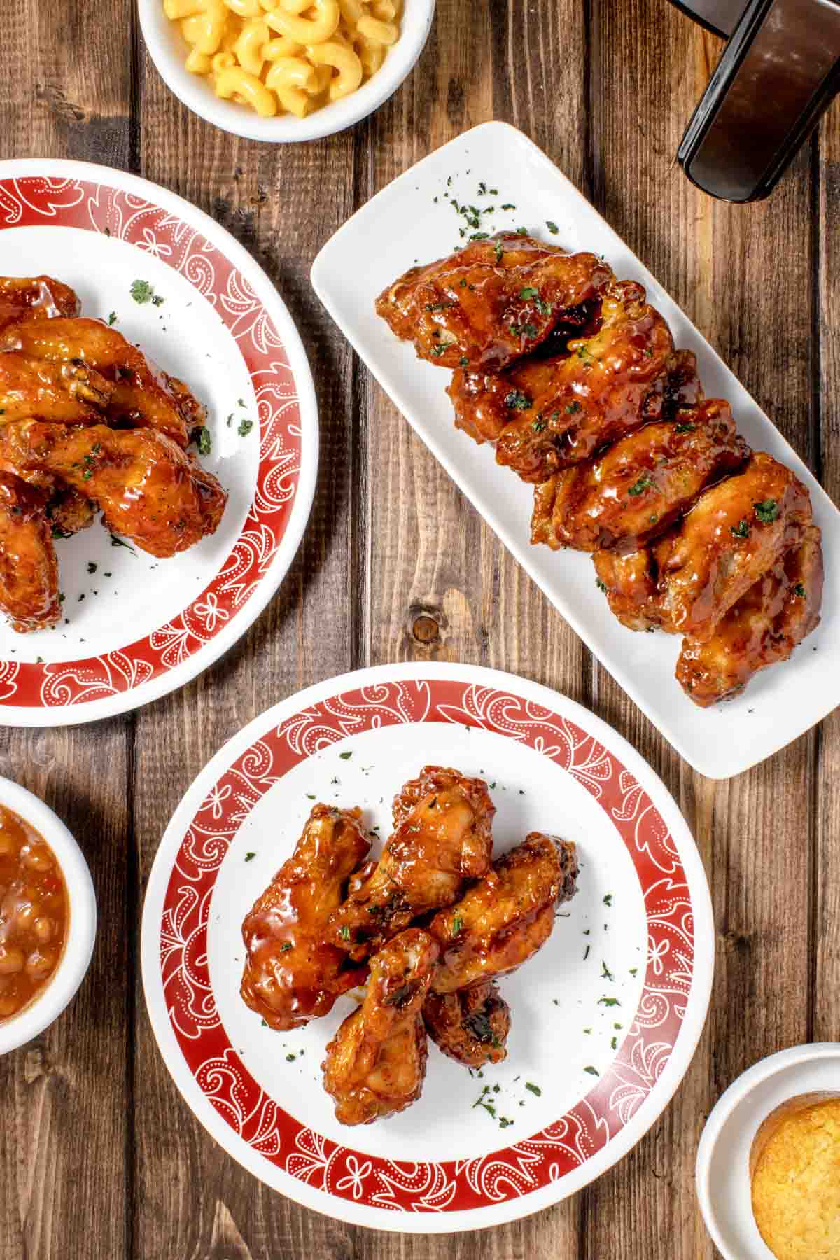 plates and trays of honey barbecue wings on a wooden table