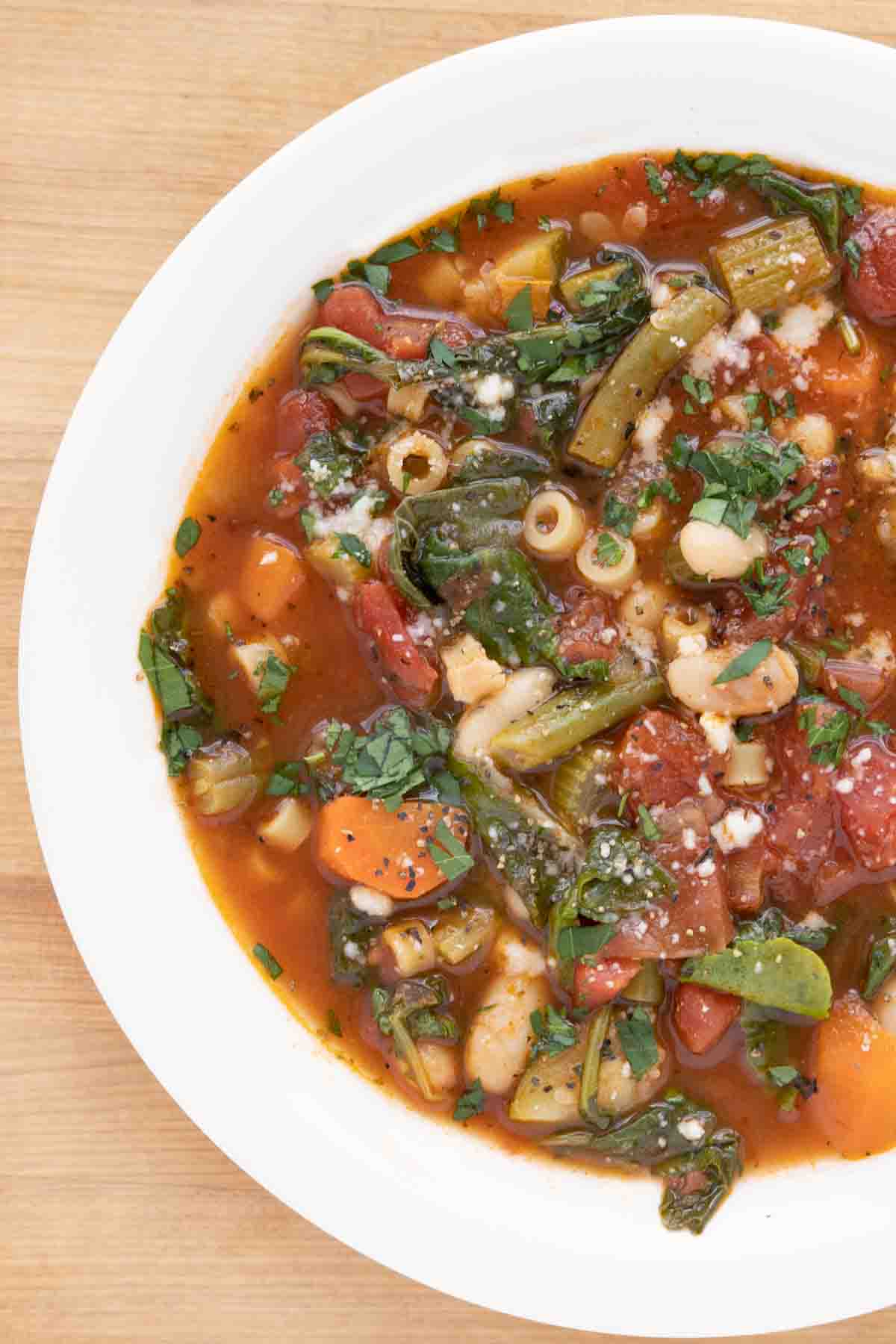 overhead partial shot of minestrone in a white bowl