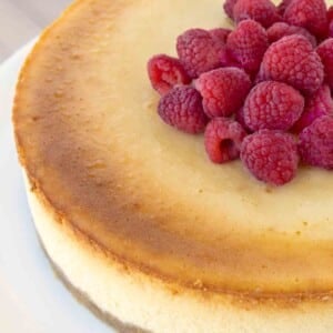 overhead partial view of Chicago style cheesecake with raspberries on a white platter