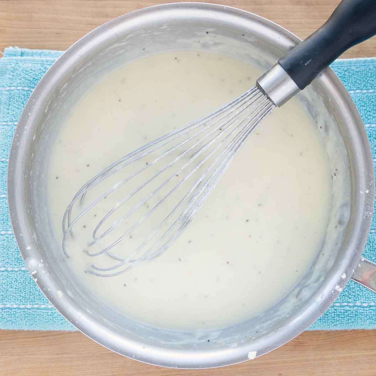 finished bechamel sauce in the pot with a wire whisk