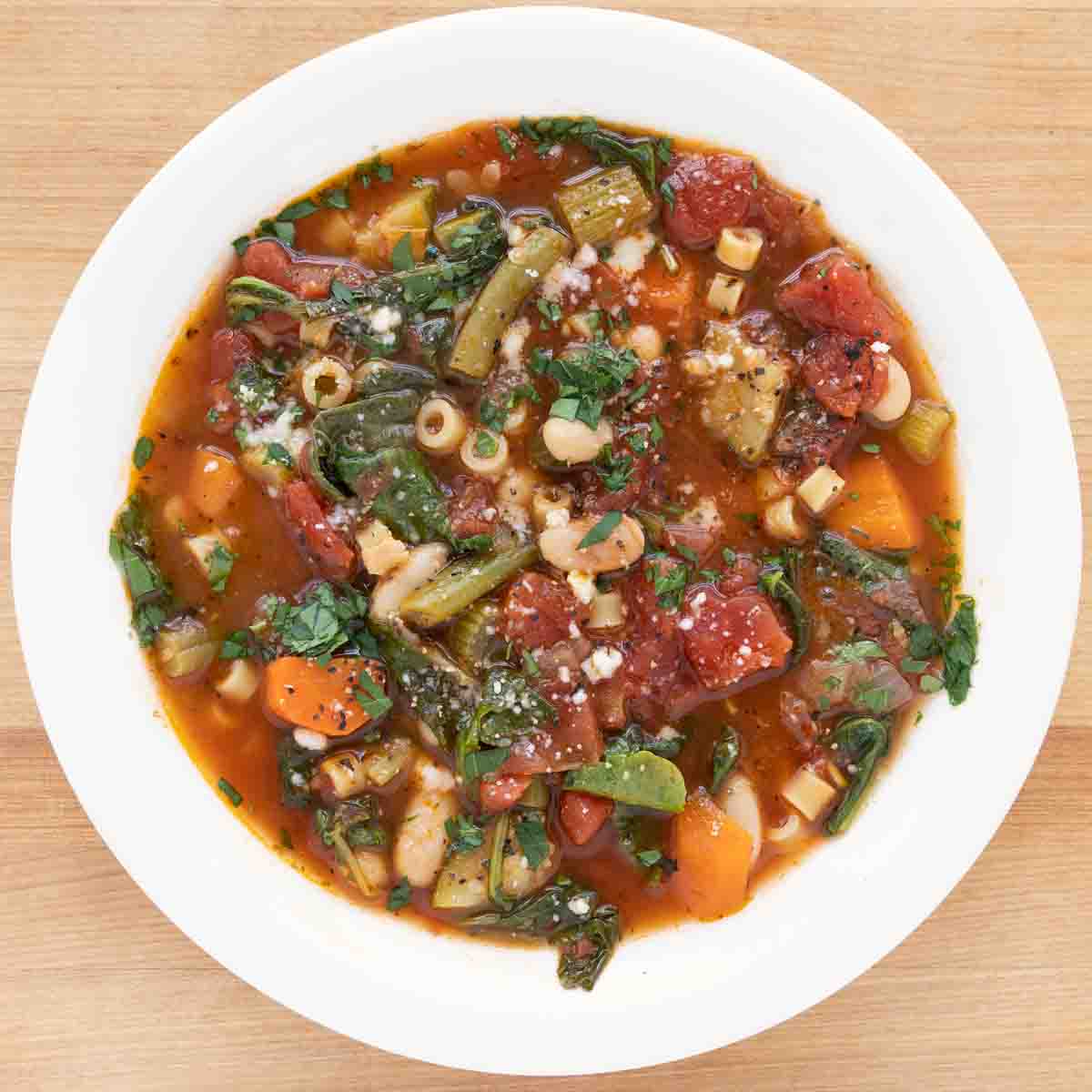 overhead shot of minestrone in a white bowl