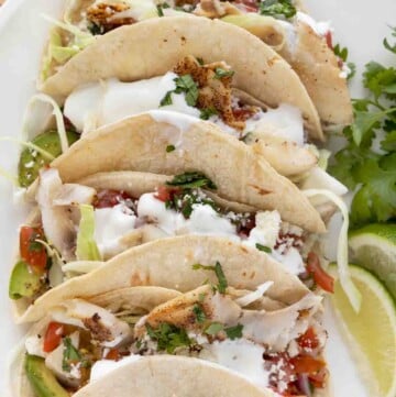 close up view of 3 tacos on a white plate.
