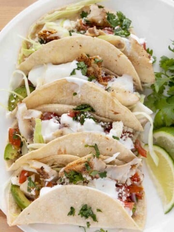 close up view of 3 tacos on a white plate.