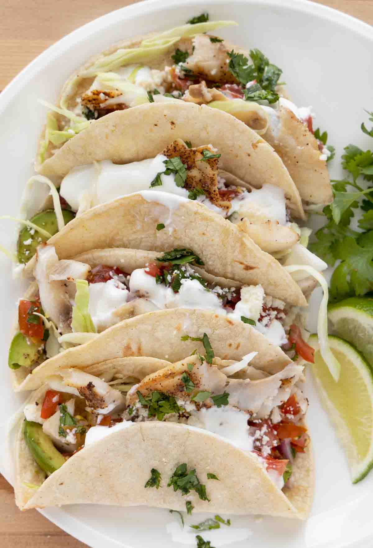 close up view of 3 tacos on a white plate.