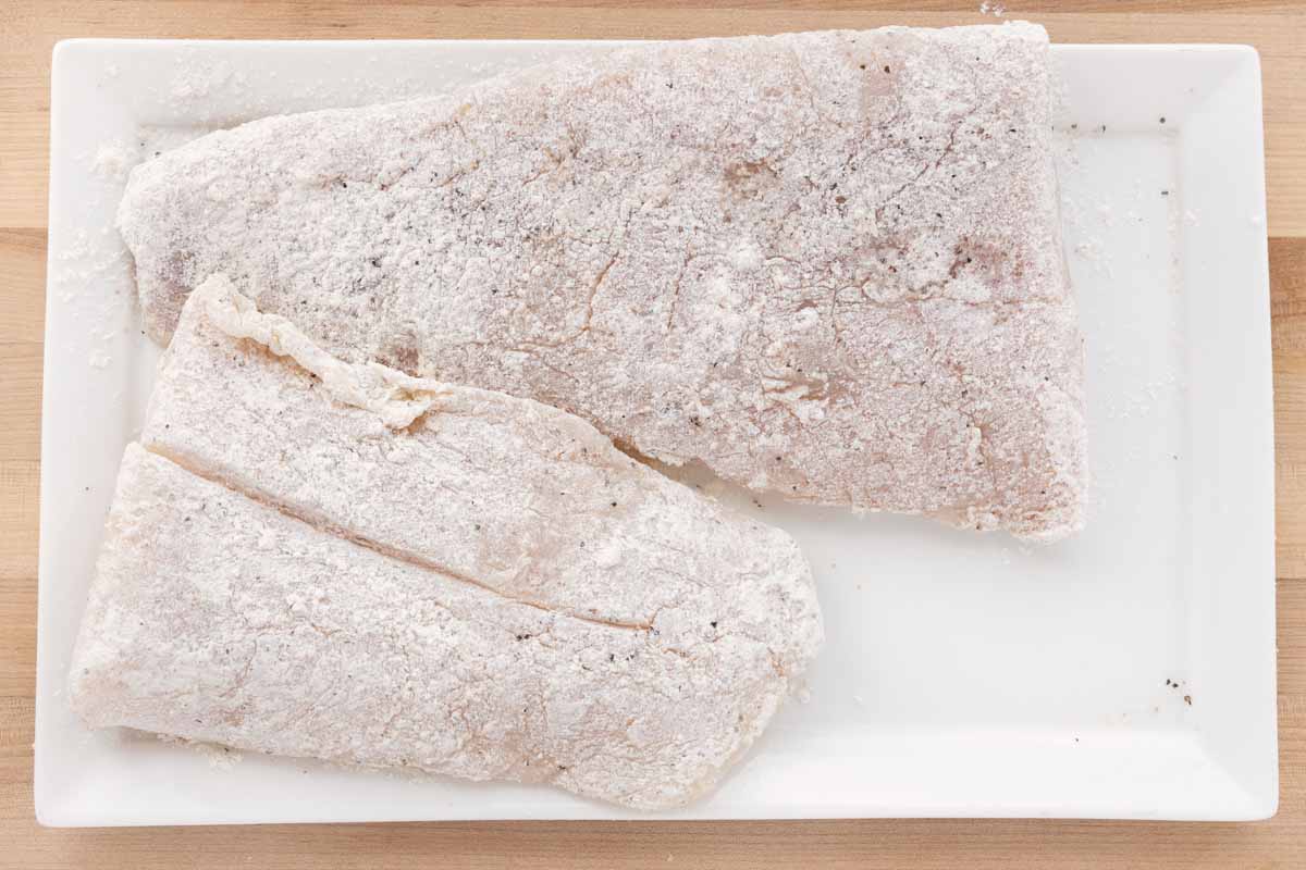 rockfish fillets coated with seasoned flour on a white platter