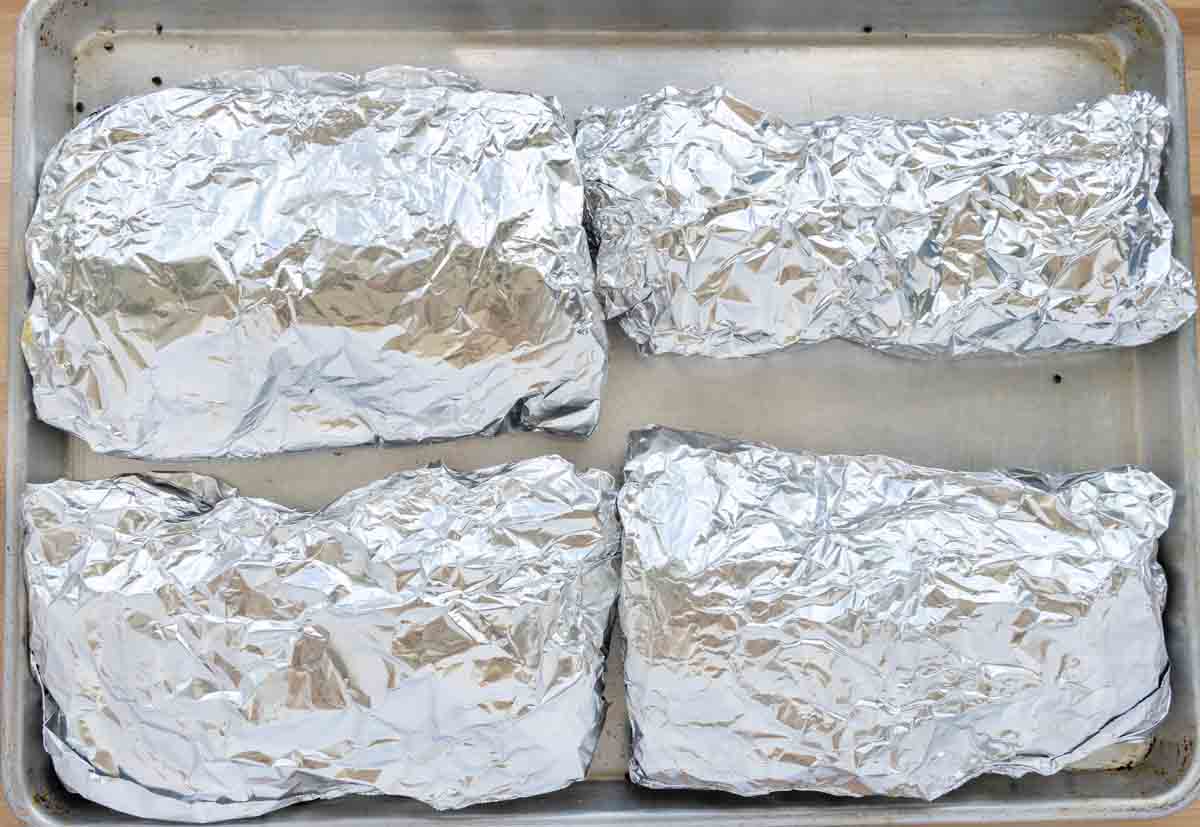 four half racks of ribs wrapped in foil.