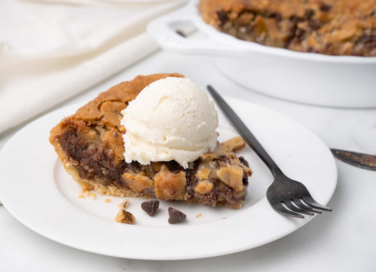 slice of tollhouse cookie pie with ice cream on top and a fork with pie on it