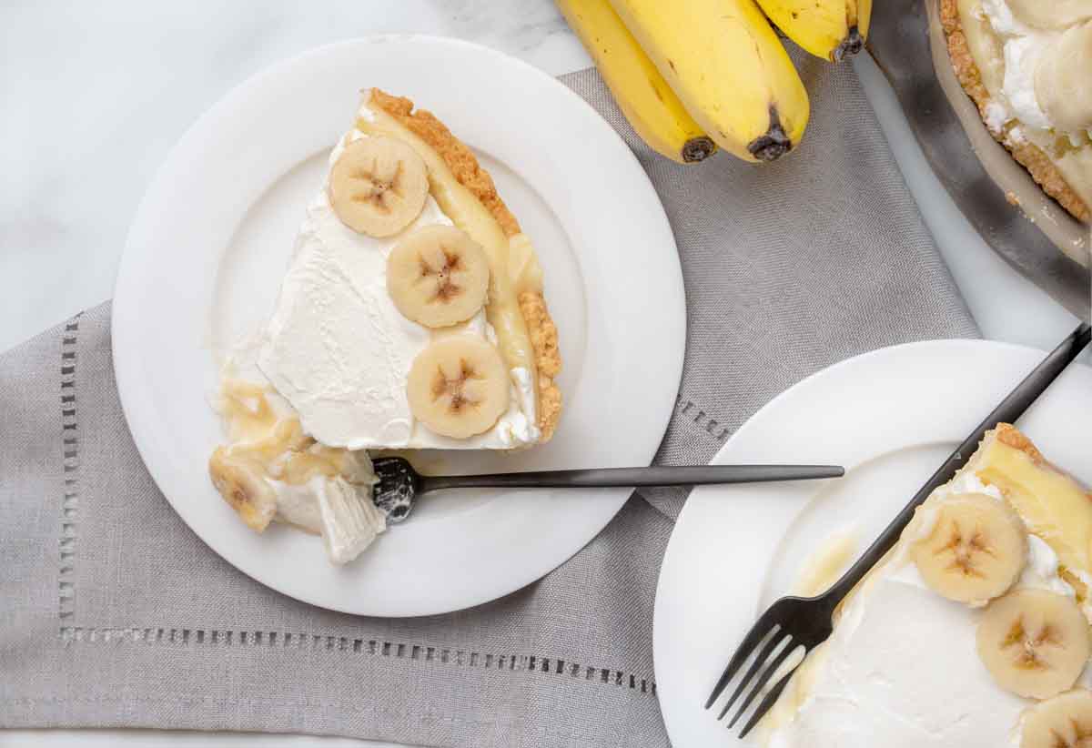 banana cream pie slices on white plates with forks