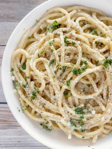 partial view of cacio e pepe in a white bowl