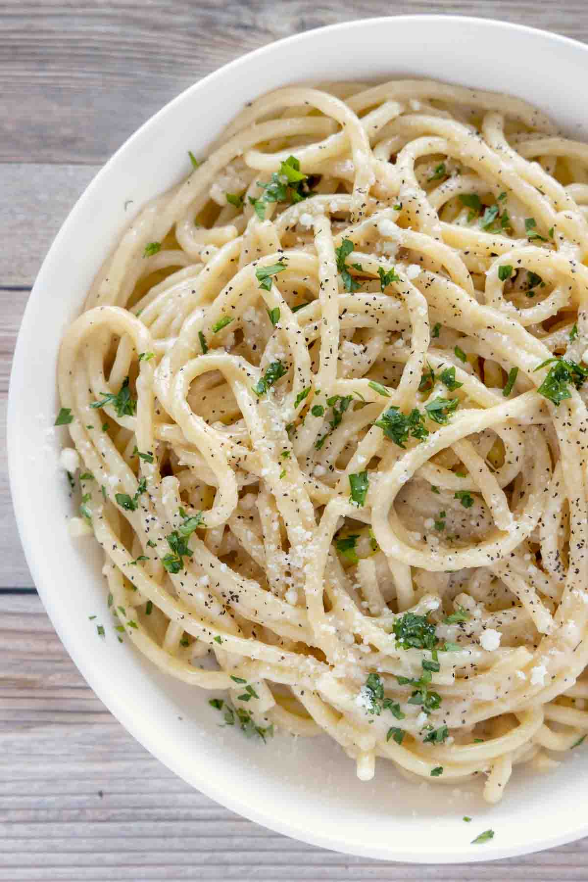 partial view of cacio e pepe in a white bowl