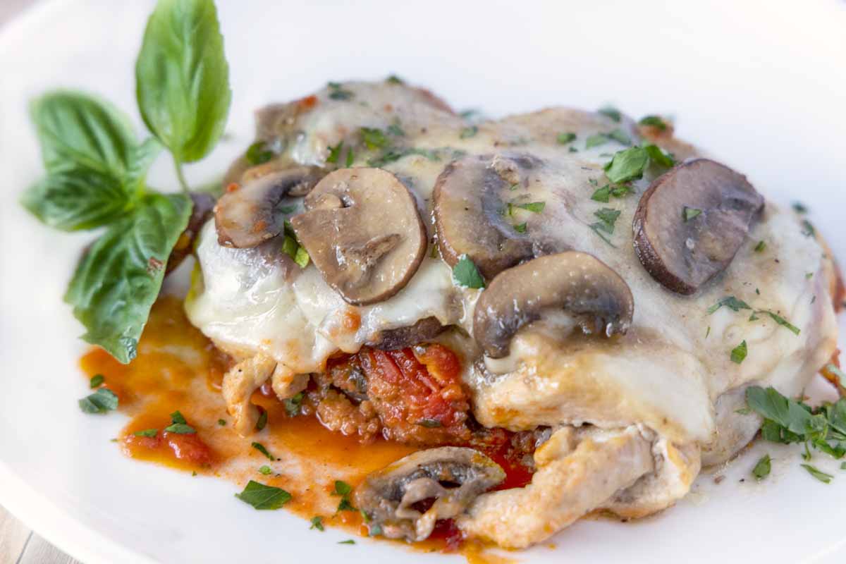chicken sorrento on a white plate with a sprig of basil