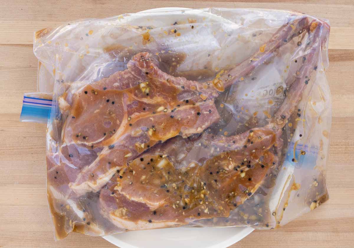 two pork chops in a zip lock bag with marinade
