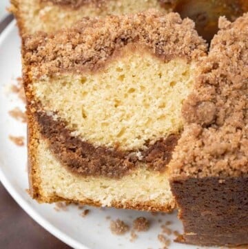 slice of cinnamon streusel coffee cake being taken out of whole cake
