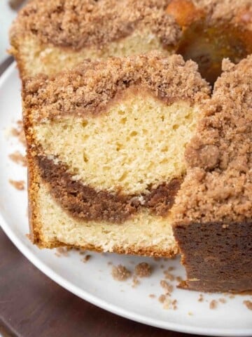 slice of cinnamon streusel coffee cake being taken out of whole cake