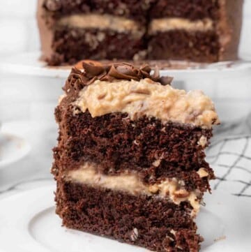 slice of German chocolate cake on a white plate with the whole cake in the background