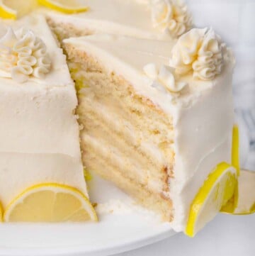 slice of lemon buttermilk being taken out of whole cake