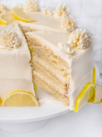 slice of lemon buttermilk being taken out of whole cake