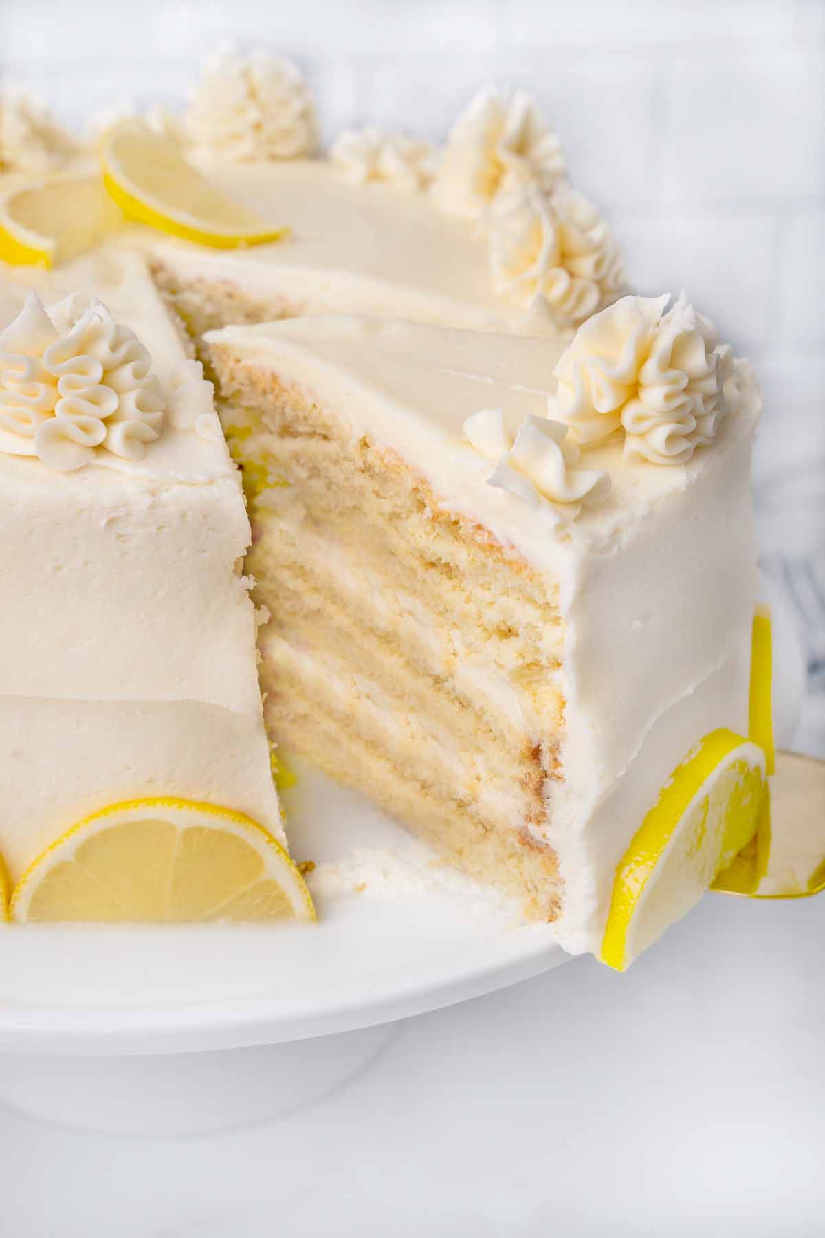 slice of lemon buttermilk being taken out of whole cake