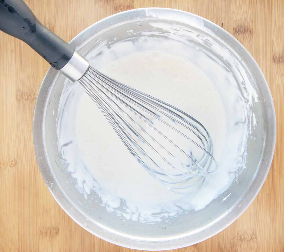 lime cream in a stainless steel bowl with a wire whisk