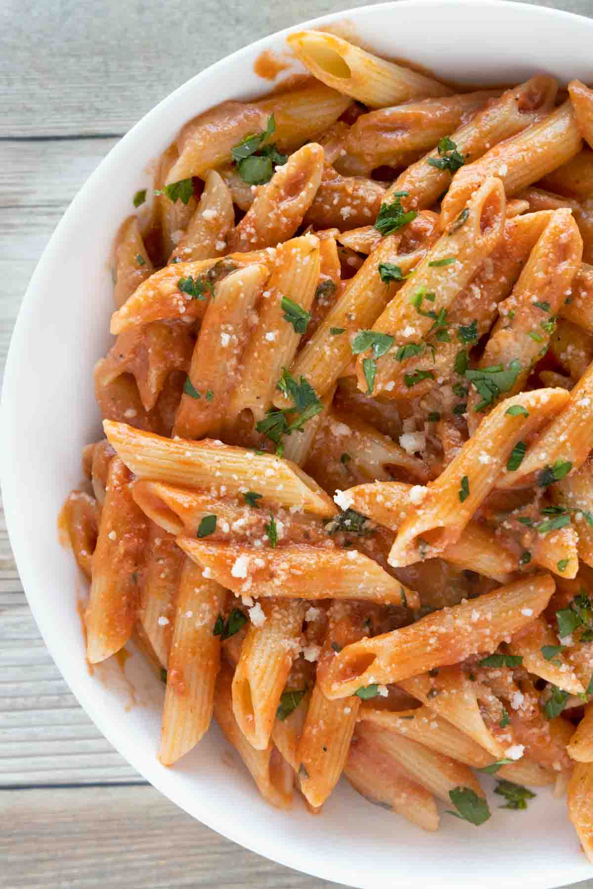 Penne alla Vodka in a white bowl garnished with chopped parsley