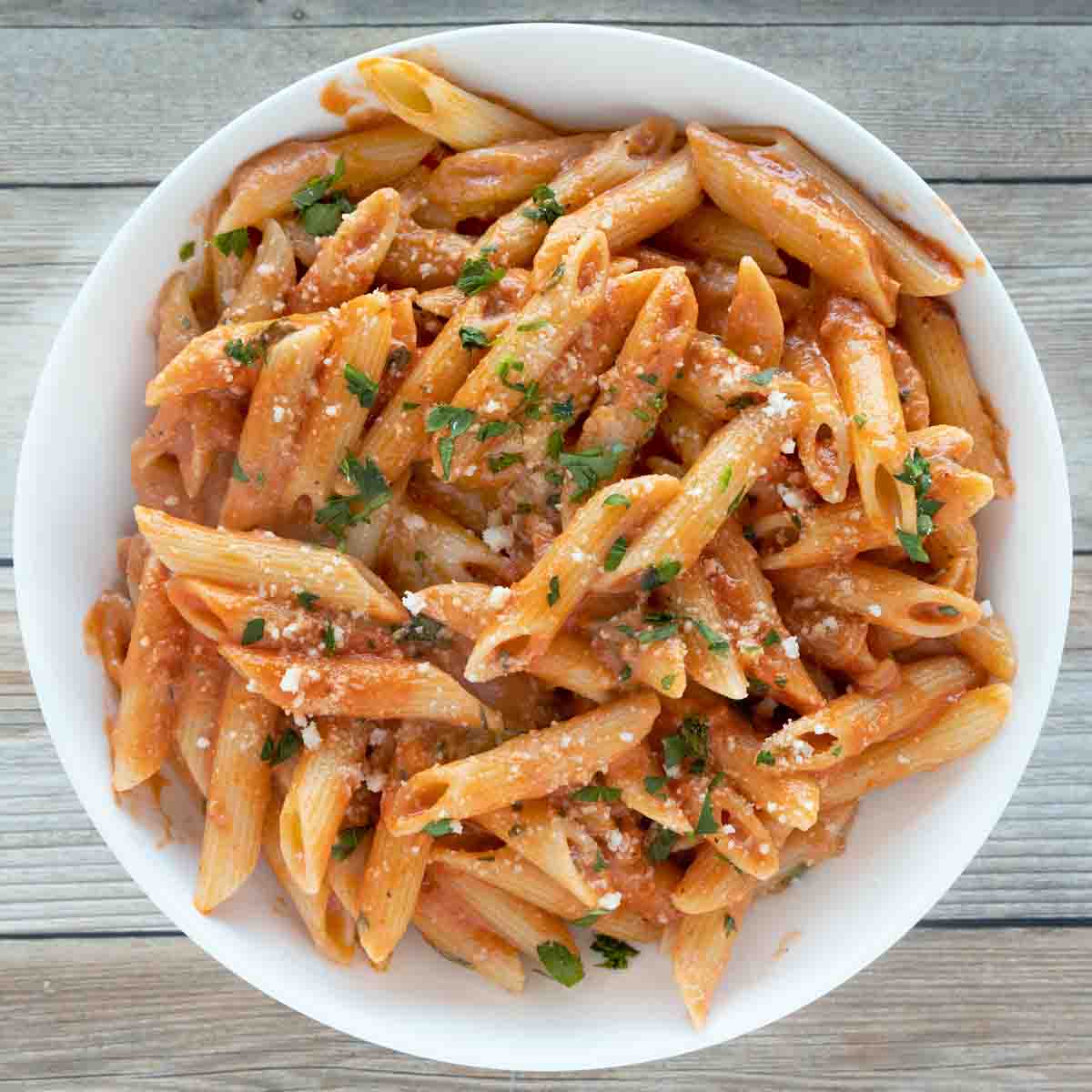 Penne alla Vodka in a white bowl garnished with chopped parsley